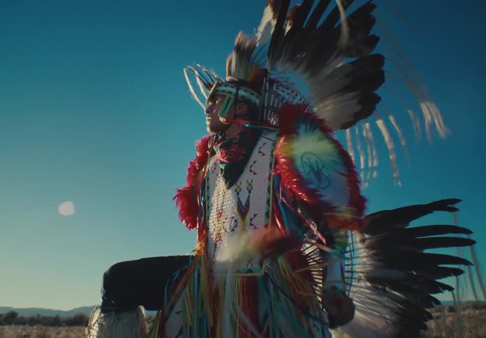 Person standing in natural setting wearing traditional native american attire