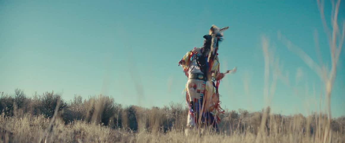 Man wearing traditional native american clothing dancing in a natural landscape