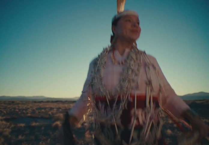 Woman from a native american tribe jumping while standing in a natural setting