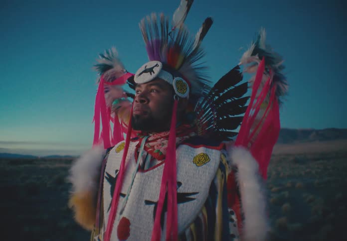 Man in a natural landscape wearing native american cultural clothing