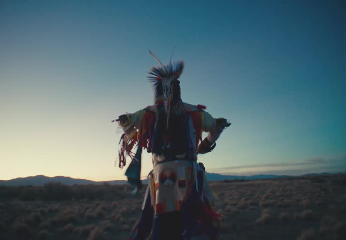 A performer in vibrant traditional attire dances under a twilight sky