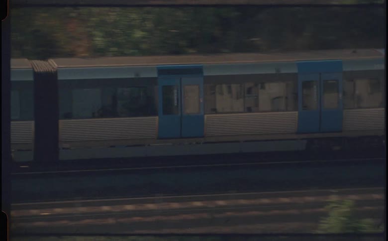A train drives by in an area with scattered trees and hills