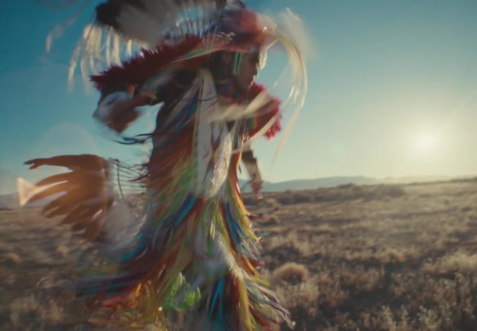 Native american person wearing tribal attire while dancing in a field