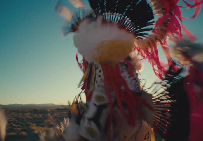 Man in native american costume dancing in desert with vegetation around