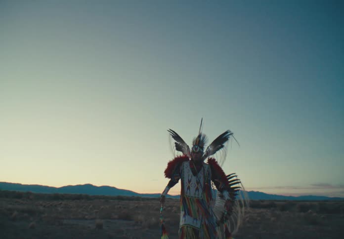 Man wearing native american costume dancing in a field
