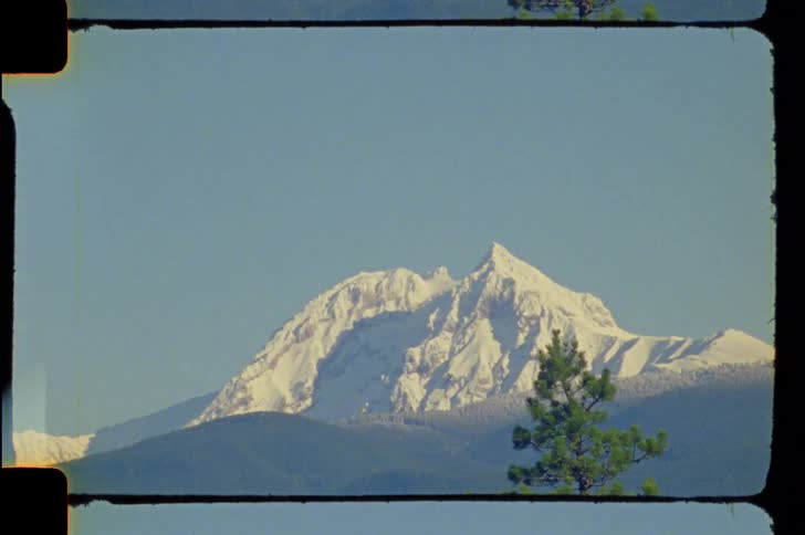 A mountaintop is covered in snow in an evergreen forest setting