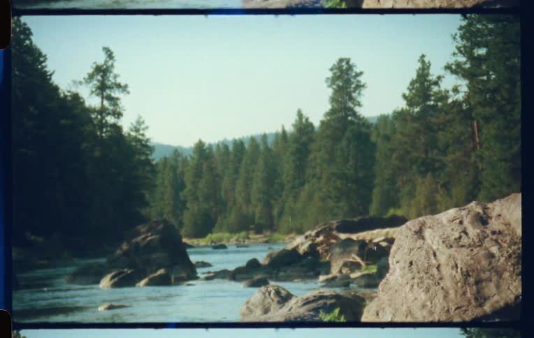 Landscape of a river surrounded by rocks and conifers