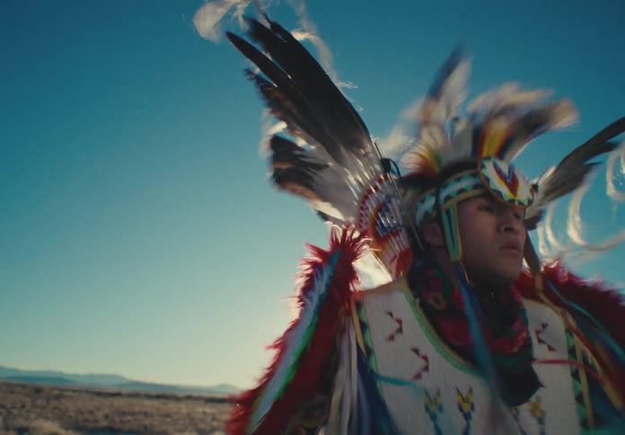 A native american dancer in vibrant regalia performs a spirited dance in a desert landscape his headdress and costume flowing in the motion