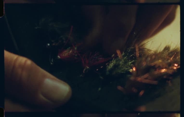 A persons finger picking up a decorative object made of colored ribbons