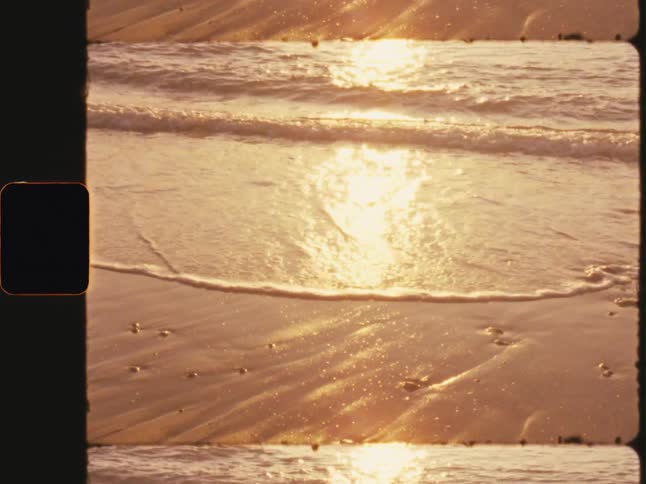 Small waves hitting the sand of a beach with buried shells