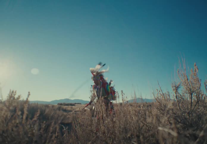 Man in traditional native american clothing dancing in a field during daytime