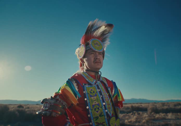 A dancer in vibrant traditional attire standing confidently in a desert landscape
