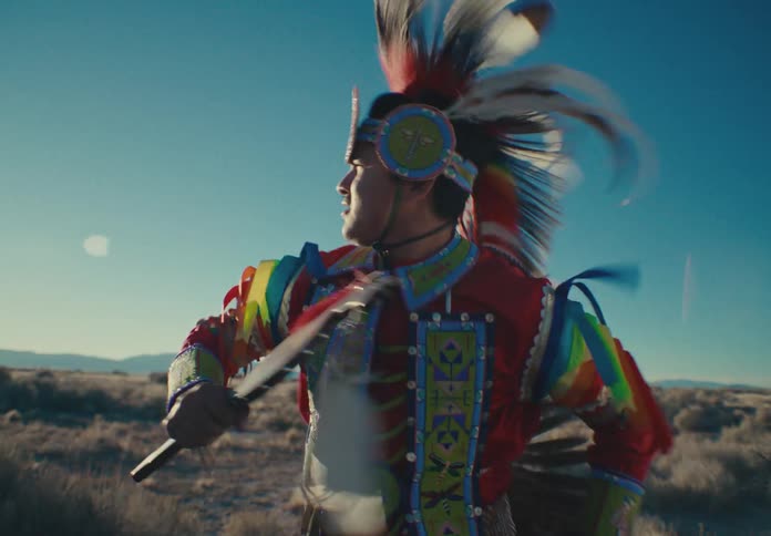 Man in native american costume dancing in natural setting during daytime
