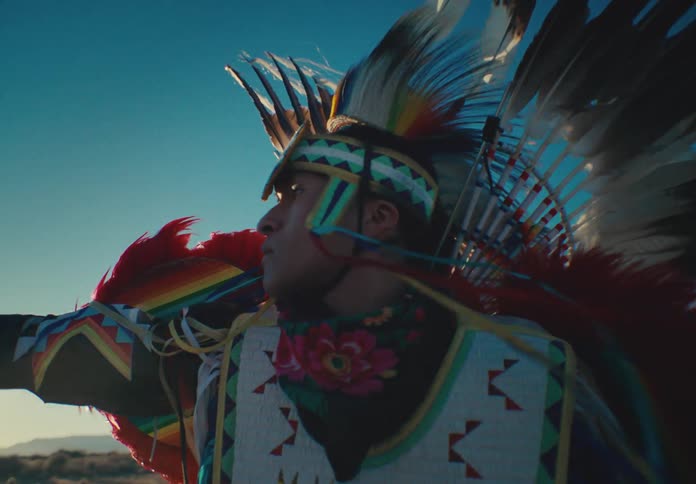Native american man belonging to a tribe with a traditional dress standing in a desert environment
