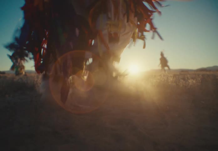 People in a field with native american costume dancing and the sun on the horizon