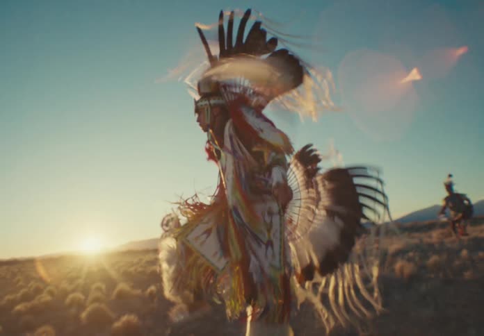 Group of people in a natural field dancing in native american costume