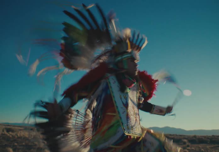 Native american person in traditional dress dancing in a natural setting