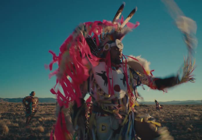Group of native american people dancing in traditional dress in a field one morning
