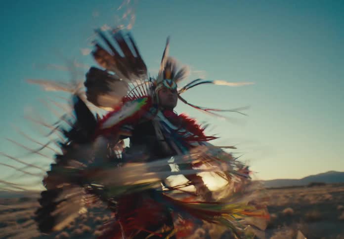 Group of people from a native american tribe in ceremonial attire dancing