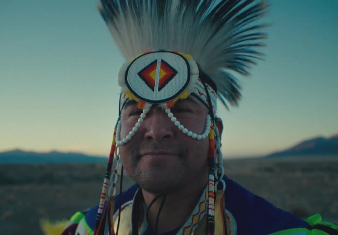 Portrait of a man wearing native american cultural clothing and mask while standing in a natural landscape