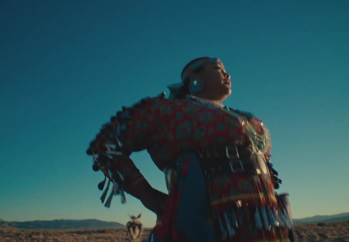 Woman of a tribe and other people in a field dancing