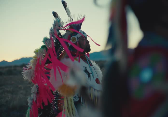 Two people in native american attire in a field