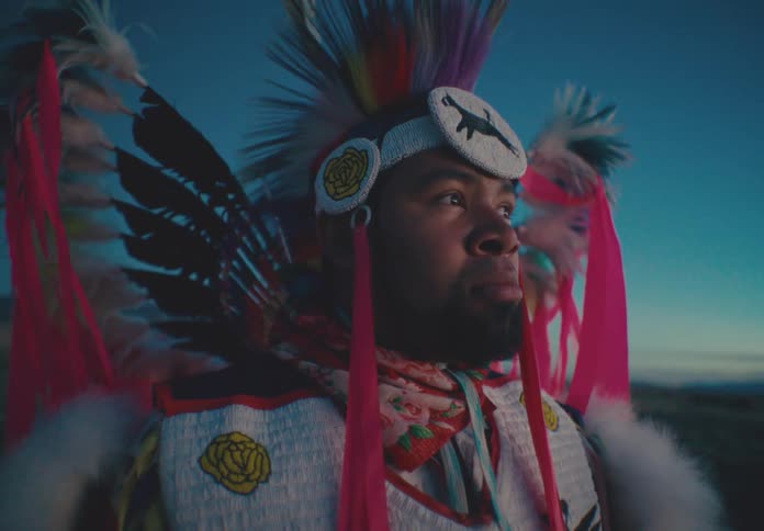 Native american man in colorful traditional dress is looking forward in natural environment
