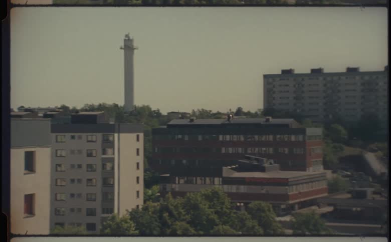 An urban landscape featuring multi story apartment buildings green spaces and a tall tower in the distance