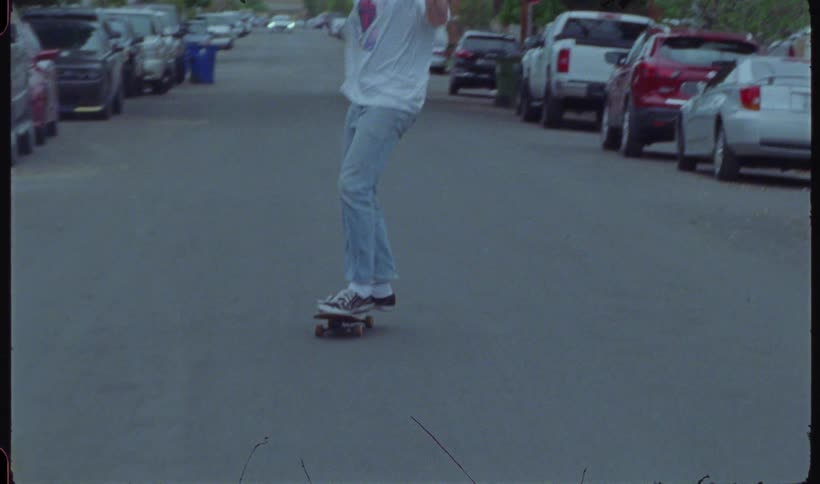 A man is riding a skateboard on a smooth road wearing jeans and sneakers