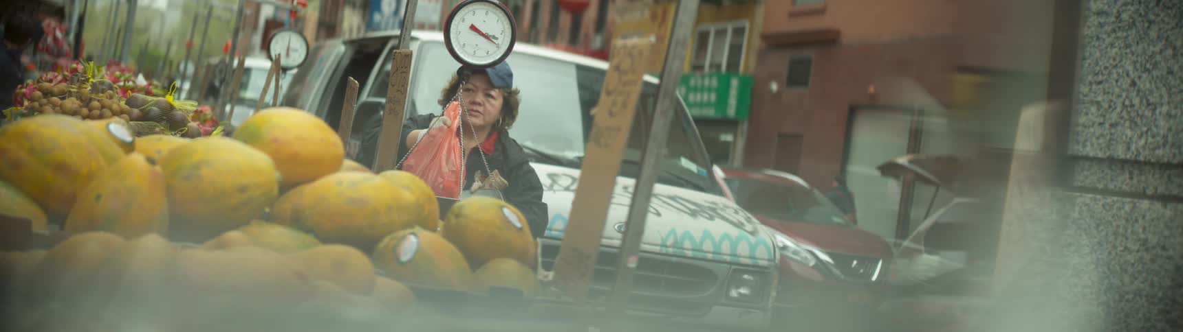 A woman weighs a bag in a scale at an outside market in the city