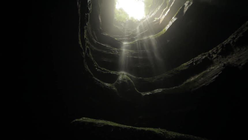 View from the bottom of a deep cavern with the sun up high