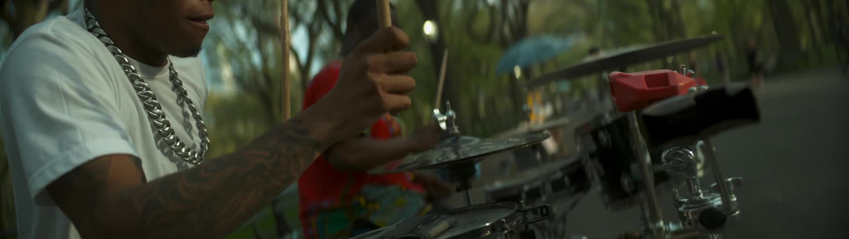 Two people drumming on drums outside in the woods