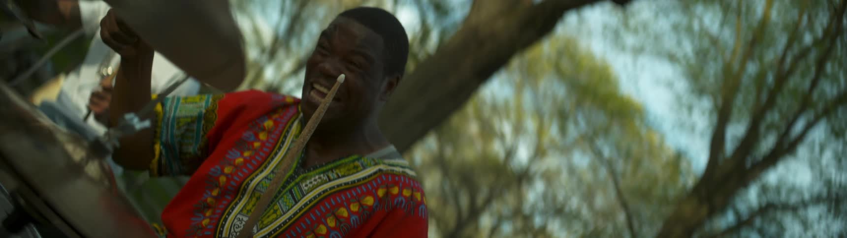 A drummer smiles and strikes a cymbal