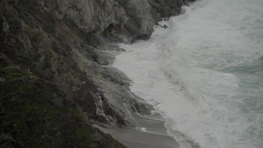 Waves crash against the rocks below