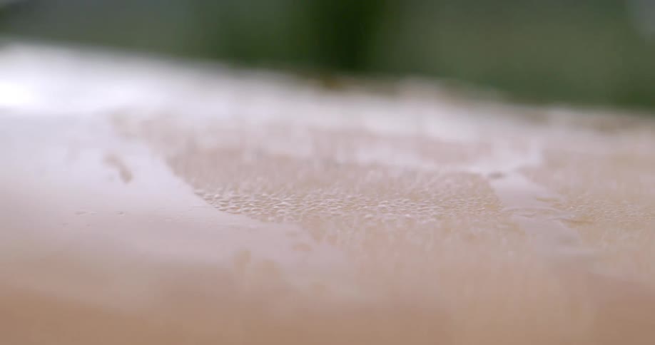 Water drops cover the exterior of a vehicle near a field during daytime