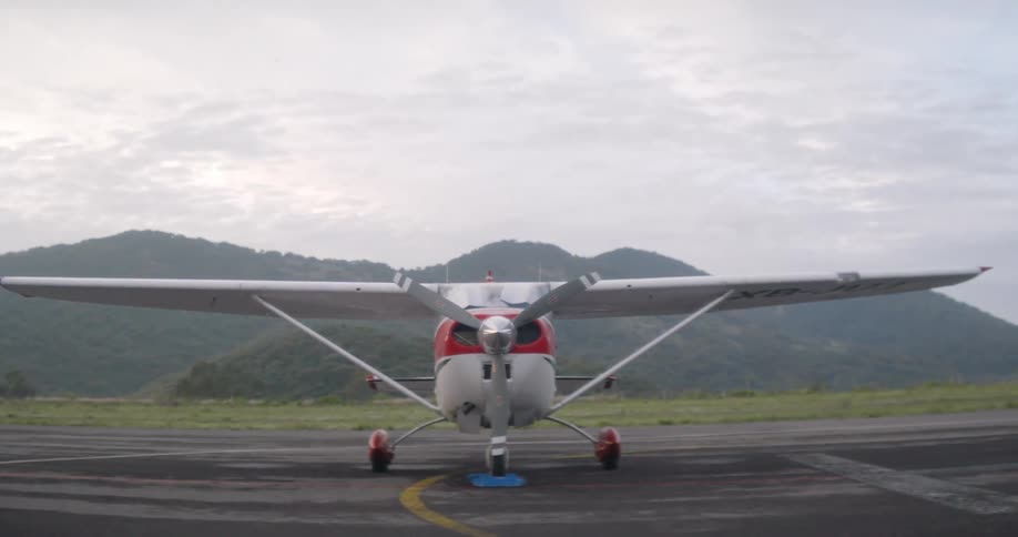 A propeller airplane is parked on a runway with mountains in the background