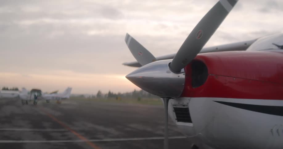 The front of a small red plane with its three propellers in front