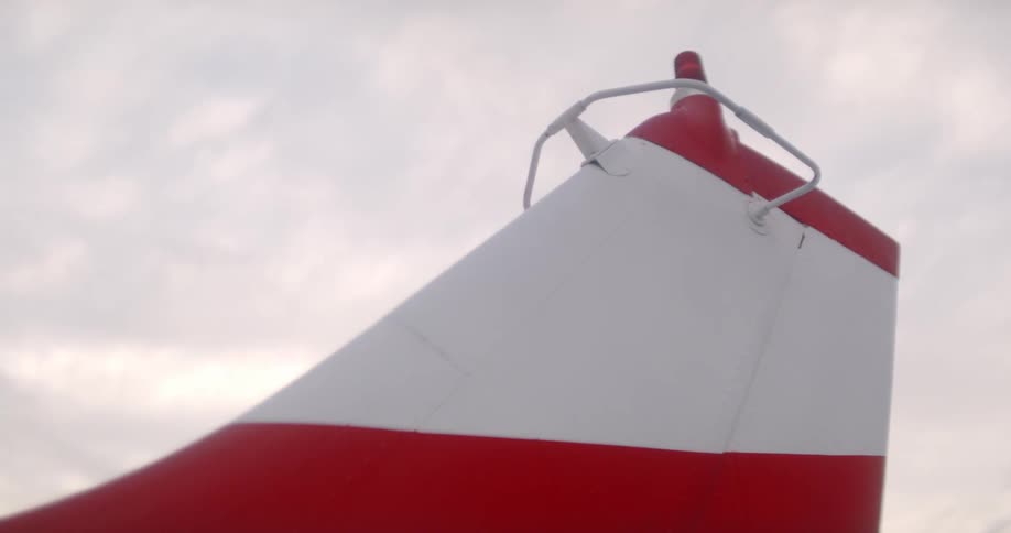 Close up of a planes red and white tail under cloudy sky