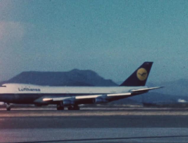 Airliner rolls down the runway at an airport near the mountains on a hazy day