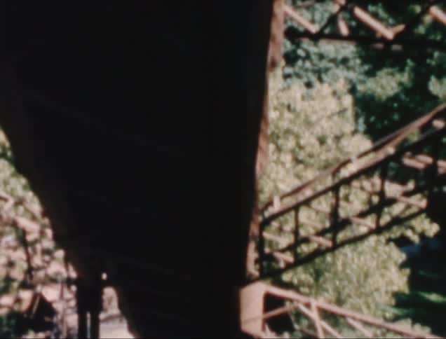 Archival footage of the internal metal trusses of a structure with trees around