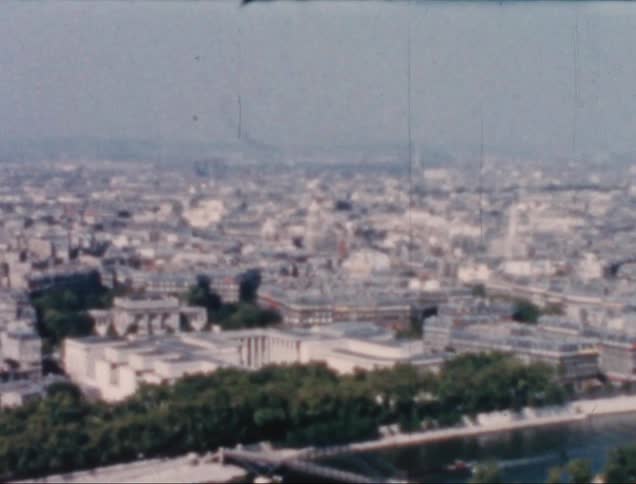 An old image of a big city with white buildings and some green trees