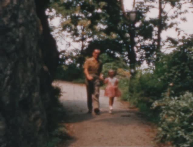 Man holding hands with a child on a path in the park