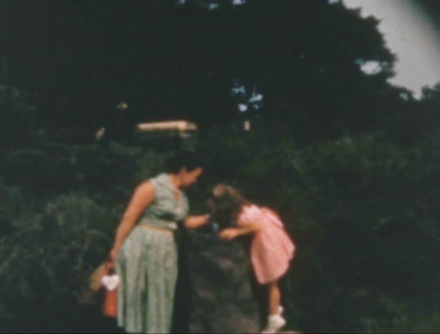 Woman in dress with little girl in natural area with trees in background