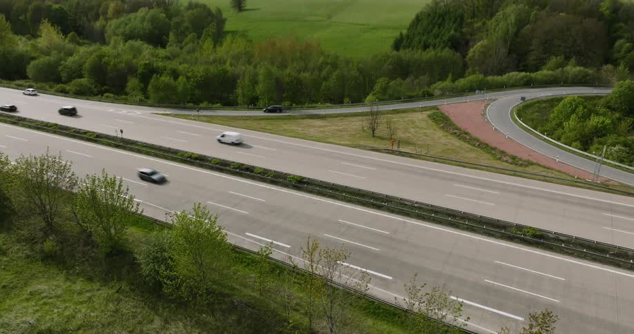 Cars driving on a highway with woods in the horizon
