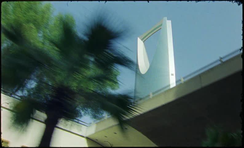 Upward view from a moving vehicle of a large modern building against a blue sky