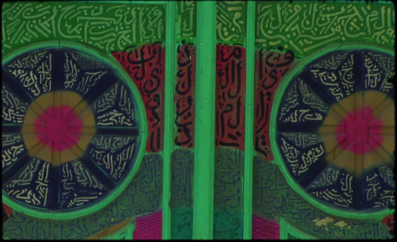 A green double exterior door with lots of decorations on a white wall