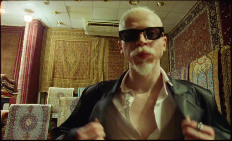 Man wearing sunglasses blazer and shirt in an indoor space
