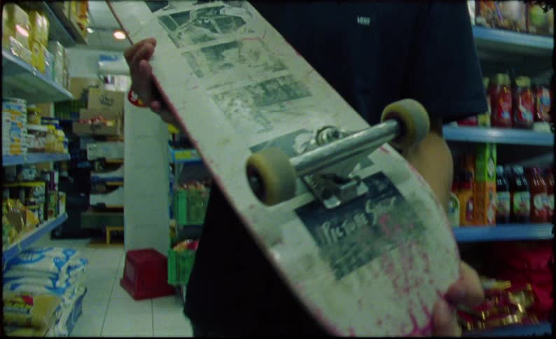 Teenager inside a supermarket holding a skateboard