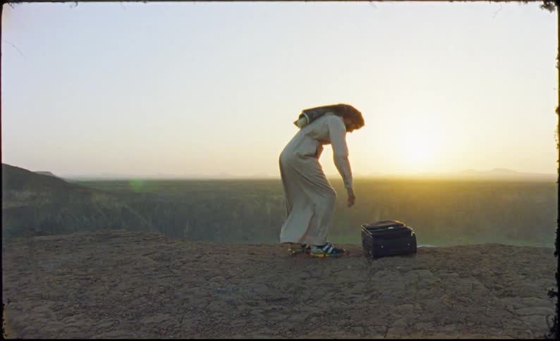 A man with a suitcase walking in a desert