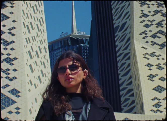 A footage of a female model standing beside an architecture